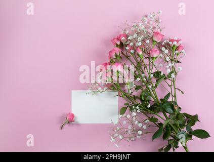 Composizione floreale. Bianco di carta rosa, fiori di rosa su sfondo rosa pastello. Giorno di San Valentino, giorno delle madri, giorno delle donne, concetto di primavera. Piatto, superiore Foto Stock