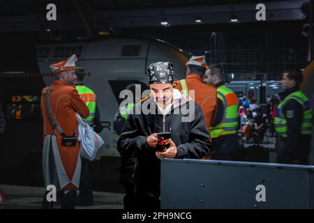 Foto di persone vestite di costumi per il Carnevale di Colonia in piedi sulla piattaforma di Koln Hbf, con un accento su un uomo vestito come un pirata utilizzando Foto Stock