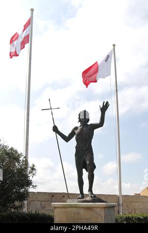 Statua di San Giovanni Battista & le bandiere dell'Ordine dei Cavalieri di Malta & la bandiera maltese. In Fort St Angelo che è un forte bastionato a Birgu, Malta, situato al centro del Grand Harbour. Foto Stock