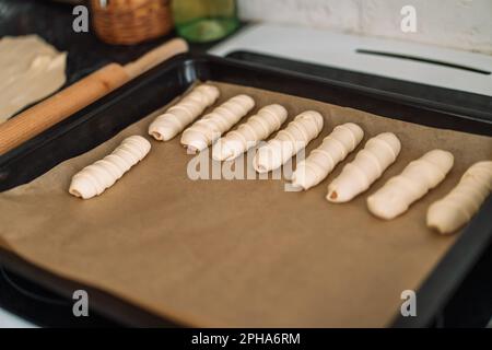 Insaccati nell'impasto su una teglia da forno con carta pergamena Foto Stock