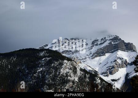 Uno splendido paesaggio caratterizzato da una splendida catena montuosa innevata con le sue vette parzialmente avvolte nelle nuvole, che offrono una vista mozzafiato Foto Stock