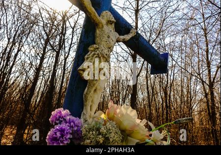 croce con gesù e fiori freschi su una montagna con foresta durante le escursioni Foto Stock