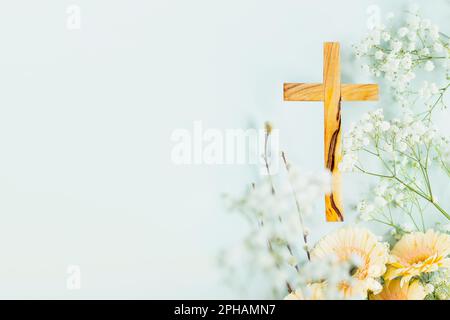 Croce di legno con fiori primaverili su sfondo blu con spazio copia. Religione sfondo. Festività religiose. Festa del Cristianesimo, Pasqua, Palme Foto Stock