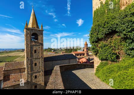 Vista della stretta strada acciottolata, dei tetti e del vecchio campanile medievale sotto il cielo blu nella piccola città di Serralunga d'Alba, Italia. Foto Stock
