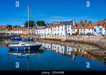 Yacht all'ancora con i riflessi colorati delle case sul lungomare al porto di St Monans a East Neuk di Fife, Scozia, Regno Unito Foto Stock