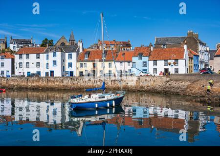 Yacht all'ancora con i riflessi colorati delle case sul lungomare al porto di St Monans a East Neuk di Fife, Scozia, Regno Unito Foto Stock