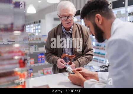 Giovane farmacista che spiega al cliente come dosare il farmaco. Foto Stock