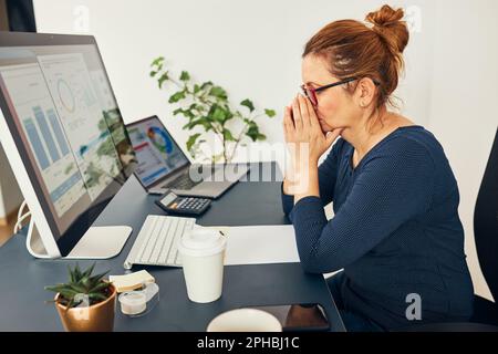 Imprenditore donna stressato si è concentrato sulla risoluzione del lavoro difficile. Donna d'affari confusa che pensa duro guardando i numeri e le tabelle sullo schermo seduto a. Foto Stock