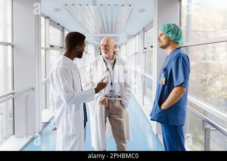 Medici e medici che discutono mentre sono in piedi in corridoio all'ospedale Foto Stock