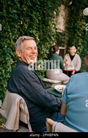 Buon uomo anziano seduto sulla sedia al ristorante Foto Stock