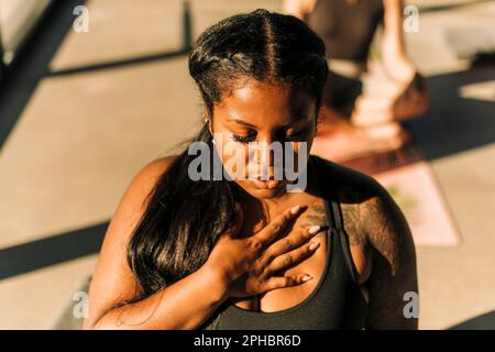 Donna più grande con mano sul petto esercitarsi di respirazione al centro di ritiro Foto Stock