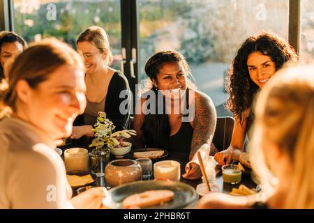 Una donna felice comunica con le amiche durante la colazione al centro di ritiro Foto Stock