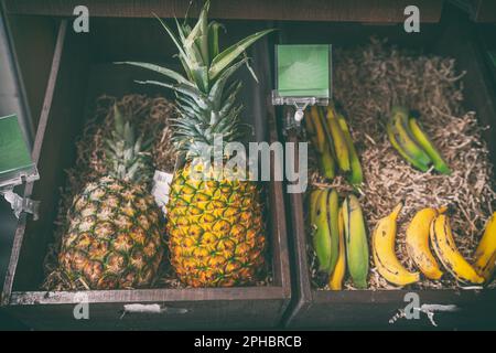 Anananas e frutti di banana in vendita al mercato agricolo alimenti biologici naturali. Frutta in cesto di legno Foto Stock