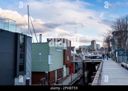 Case galleggianti e lo skyline della città di Vancouver visto dal lungomare e banchine di Granville Island nel tardo pomeriggio in una giornata di primavera. Foto Stock