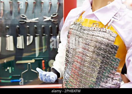 Grembiule a catena per disossamento di carne e coltelli in mostra Foto Stock