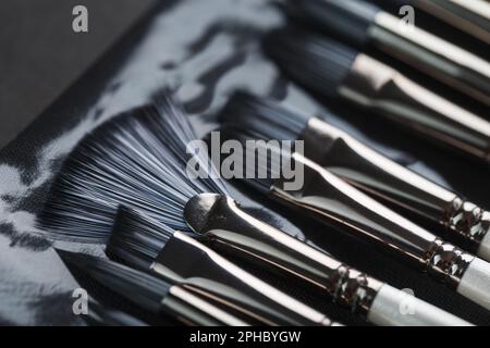 Tubi di verniciatura, pennelli per pittura e palette su vecchio sfondo in legno. Primo piano Foto Stock