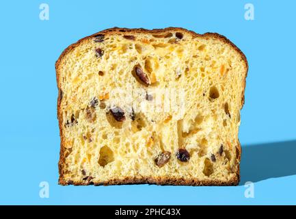 Sezione trasversale da un panettone fatto in casa, minimalista su un tavolo blu. Consistenza panettone in pasta madre in luce brillante. Foto Stock