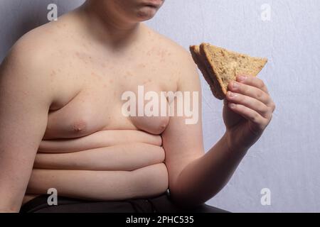 Un ragazzo caucasico in sovrappeso che mangia un panino Foto Stock