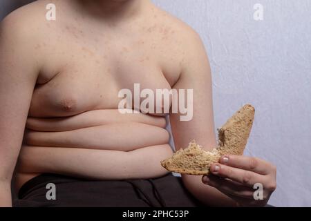 Un ragazzo caucasico in sovrappeso che mangia un panino Foto Stock