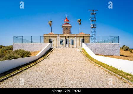 Faro recintato di Farol da Ponta da Piedade a Lagos catturato dal vialetto in una giornata di sole con cielo blu, che mostra la sua torre e il cancello. Foto Stock