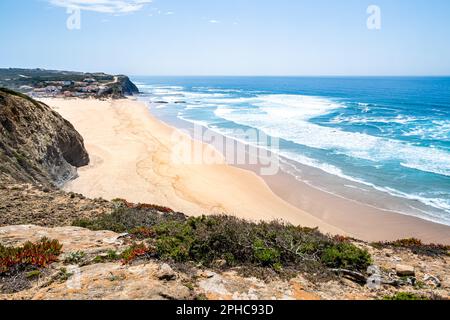 Vista panoramica da un'alta scogliera della spiaggia di Praia de Monte Clérigo con la vasta distesa dell'Oceano Atlantico che si estende in lontananza. Foto Stock