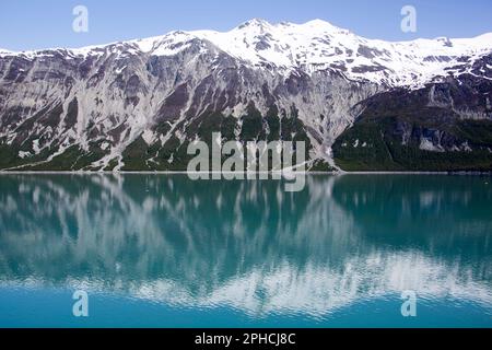 La vista primaverile delle montagne innevate e delle acque calme con riflessi nel parco nazionale di Glacier Bay (Alaska). Foto Stock