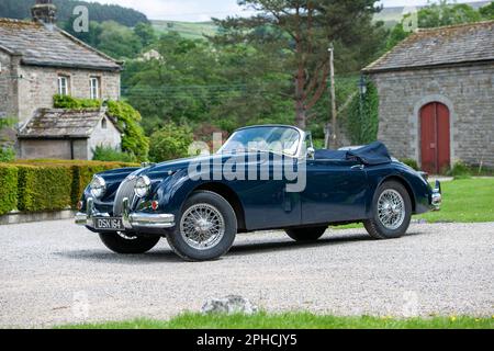 Classic British Jaguar XK150 cabriolet parcheggiato in un villaggio dello Yorkshire in una soleggiata giornata estiva Foto Stock