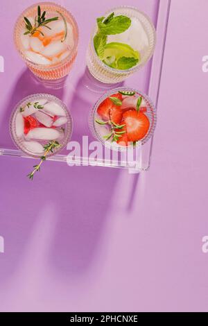 Bevande rinfrescanti estive in un vassoio di plastica sullo sfondo viola, vista dall'alto Foto Stock