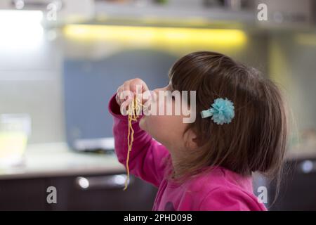 Immagine di una adorabile bruna che mangia spaghetti con le mani. Foto Stock