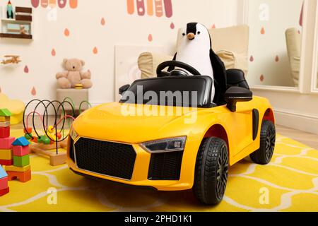 Auto elettrica per bambini con pinguino giocattolo nella sala giochi Foto Stock