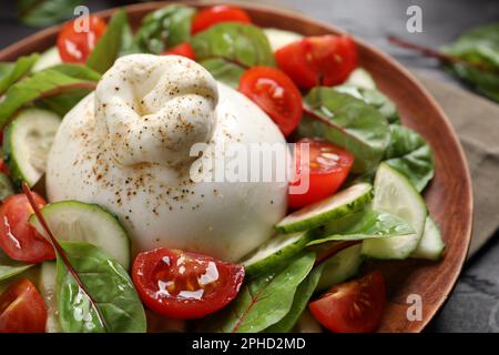 Deliziosa insalata di burrata con pomodori e cetrioli su piatto, primo piano Foto Stock