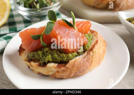 Deliziosa bruschetta con salmone e pesto al tavolo, primo piano Foto Stock