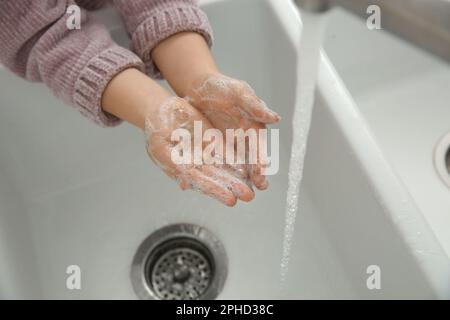 Bambina lavando le mani con sapone liquido, primo piano Foto Stock