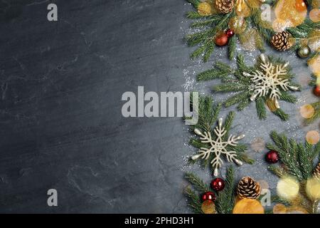 Composizione piatta con rami di abete e decorazioni natalizie su sfondo nero, spazio per testo. Design del biglietto d'auguri Foto Stock