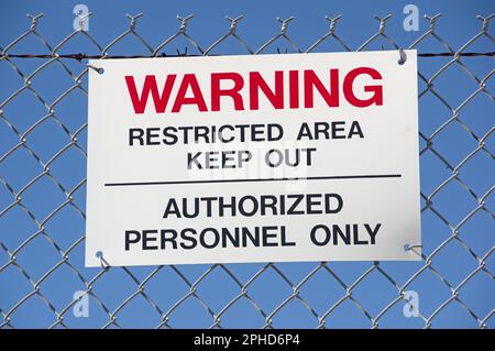 avvertenza aree ad accesso limitato tenere fuori il personale autorizzato apporre la firma solo su una recinzione metallica con sfondo blu cielo Foto Stock