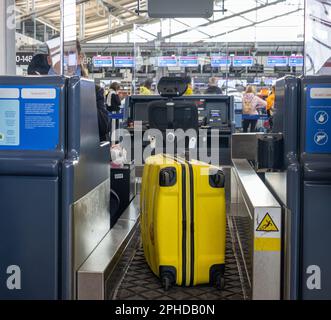 Valigia gialla del passeggero su un nastro trasportatore durante il check-in in un aeroporto internazionale Foto Stock