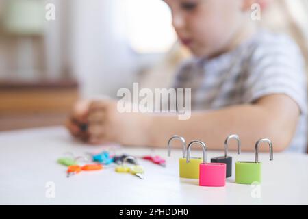 Il bambino lavora con materiale Montessori con serrature colorate. Raccoglie i tasti. Sviluppa le abilità motorie fini. Foto Stock