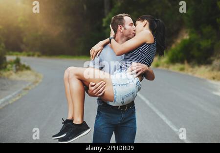Il romanticismo da fiaba esiste. un giovane uomo che porta romanticamente la sua ragazza giù una strada all'aperto. Foto Stock