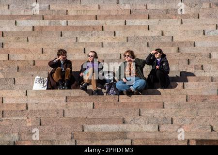 I giovani seduti sui gradini della Cattedrale di Helsinki in una soleggiata giornata primaverile nel quartiere Kruununhaka di Helsinki, Finlandia Foto Stock