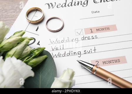 Composizione con lista di controllo per matrimoni su tavolo di legno, primo piano Foto Stock