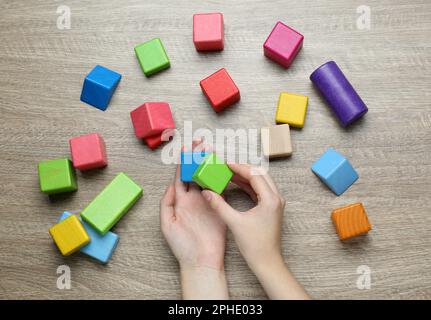 Terapista ABA con blocchi da costruzione colorati al tavolo di legno, vista dall'alto Foto Stock