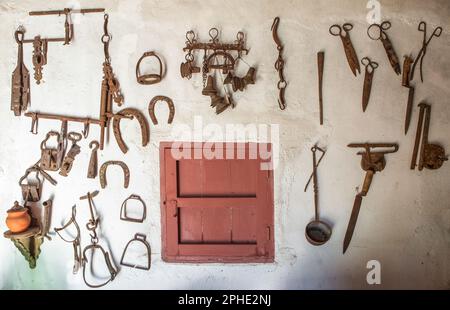 Vecchi attrezzi agricoli appesi a un muro. Sfondo in stile country Foto Stock