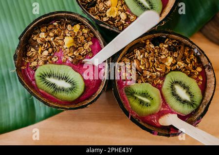 Un primo piano di una varietà di dessert serviti in una conchiglia di cocco appena raccolta, che mostra i colori vibranti e i sapori delle prelibatezze Foto Stock