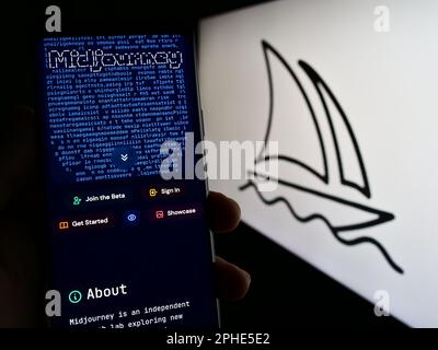 Persona che tiene il cellulare con il sito web della società di intelligenza artificiale Midjourney Inc. Sullo schermo con il logo. Messa a fuoco al centro del display del telefono. Foto Stock