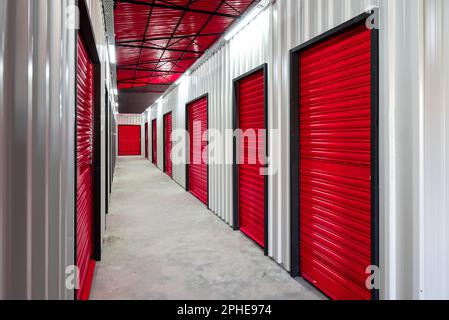 Corridoio dell'unità di self-storage con porte rosse. Unità di stoccaggio a noleggio Foto Stock