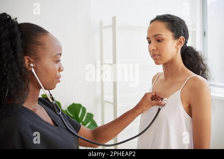 La dottoressa nera ascolta il battito cardiaco del paziente al controllo medico Foto Stock