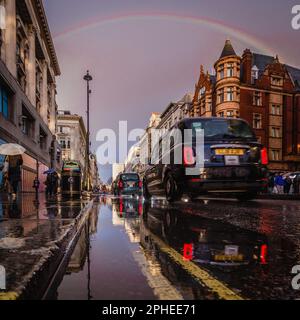 Un iconico taxi nero si riflette in una pozza su Oxford Street dopo la pioggia a Londra. Foto Stock