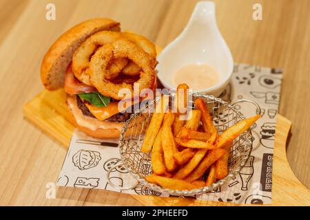 Un colpo dall'alto di un tagliere in legno con un hamburger appena cucinato e una porzione di patatine fritte dorate Foto Stock