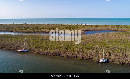 Una foto aerea di due barche a vela bianche ormeggiate in una zona paludosa poco profonda a Boca Grande, Florida. Foto Stock