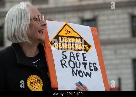 Un attivista liberaldemocratico che chiede "Safe routes Now” in un rally contro il controverso disegno di legge sull'immigrazione illegale fuori dal Palazzo di Westminster Foto Stock